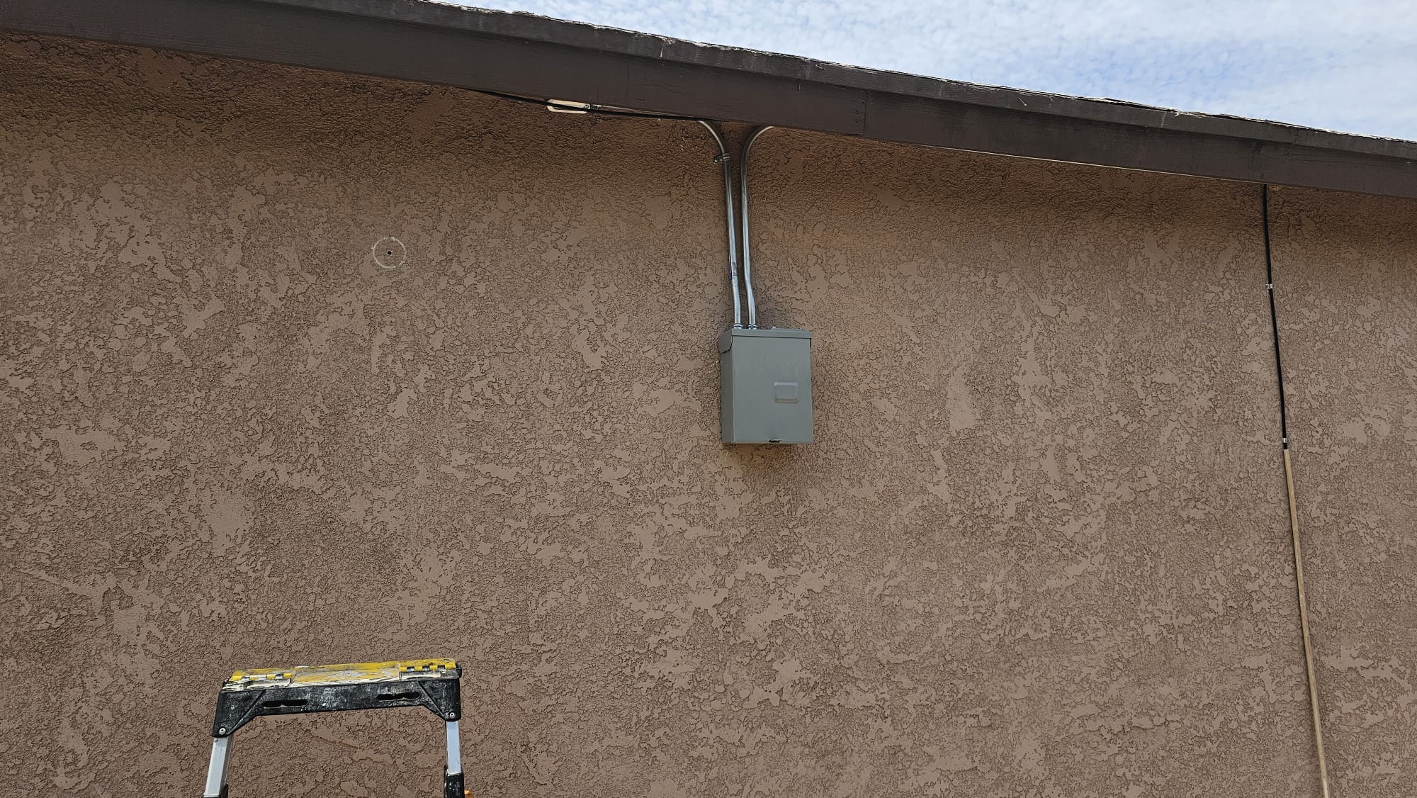 Desconectador eléctrico y canalización instalados en un muro exterior